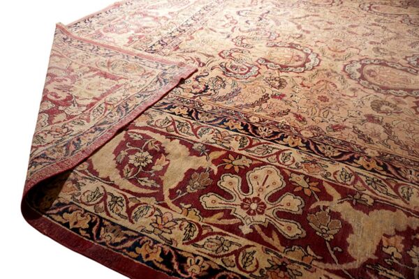 Traditional beige and deep red rug detail showing complex floral patterns and a folded corner.