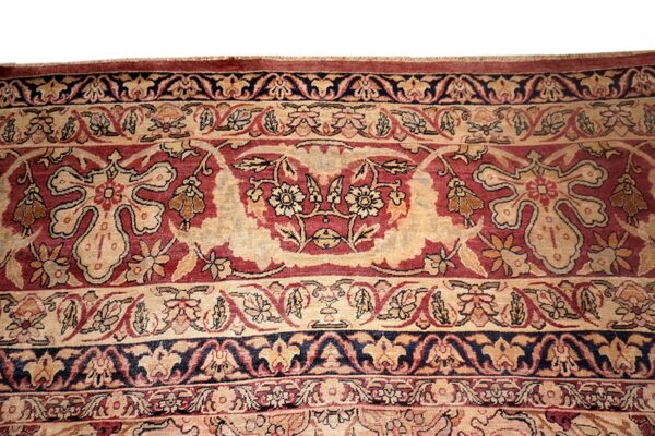 Detailed view of a dense, traditional rug pattern in beige, maroon, and navy blue.