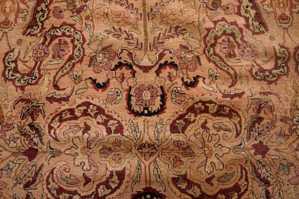 Low-pile rug detail showing flowing paisley and floral patterns on a dusty tan field with burgundy accents.