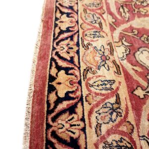 A close view of a traditional rug pattern featuring red, gold, and dark blue borders and floral motifs.