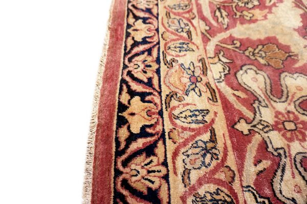 A close view of a traditional rug pattern featuring red, gold, and dark blue borders and floral motifs.