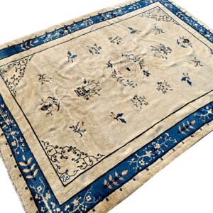Beige rug with scattered blue and brown motifs and a wide cobalt blue floral border.