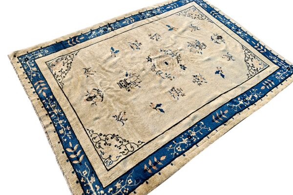 Beige rug with scattered blue and brown motifs and a wide cobalt blue floral border.