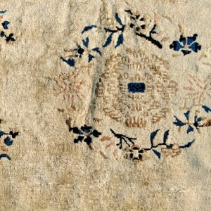 Cream rug texture with scattered dark blue, brown, and light pink blossoms around a central circular design.