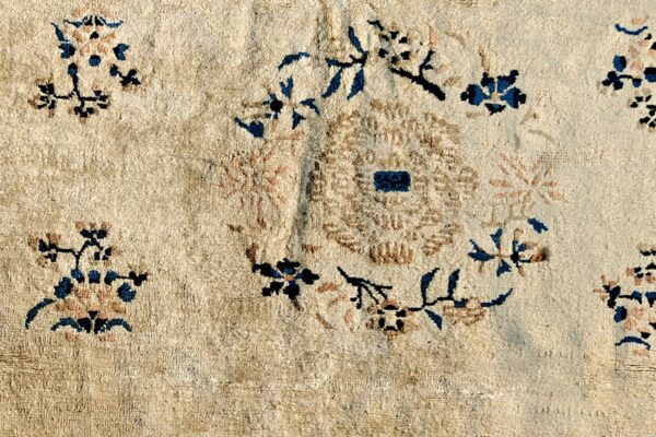 Cream rug texture with scattered dark blue, brown, and light pink blossoms around a central circular design.