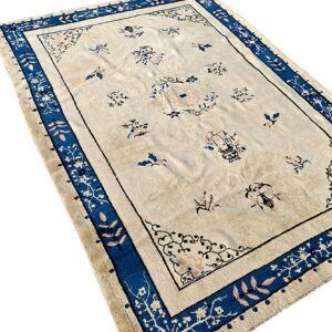 A cream rug with scattered blue floral motifs and a wide blue border with light pink leaves.