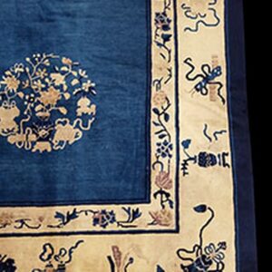 Close-up of a blue rug with a light tan border and an intricate medallion pattern in the field.