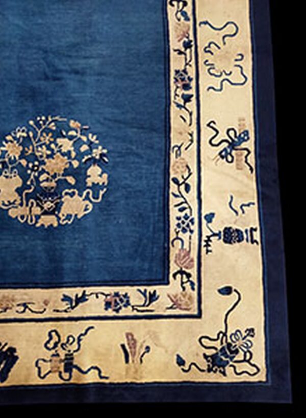 Close-up of a blue rug with a light tan border and an intricate medallion pattern in the field.