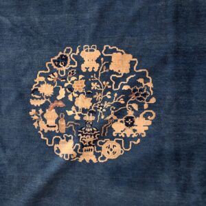 Deep blue low-pile rug centered with a beige medallion featuring detailed vases and floral motifs.