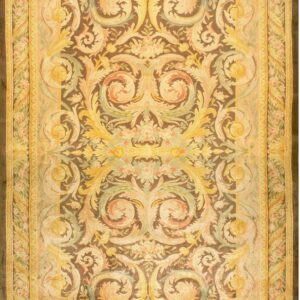 Detailed low-pile rug with yellow, peach, and green scrollwork on a dark brown central field.