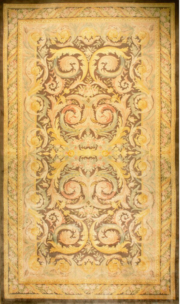 Detailed low-pile rug with yellow, peach, and green scrollwork on a dark brown central field.