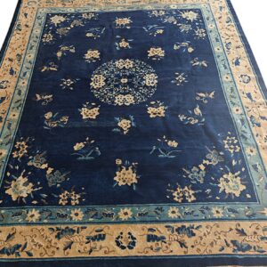 Navy blue rug featuring a repeating floral and butterfly pattern with tan and teal borders.