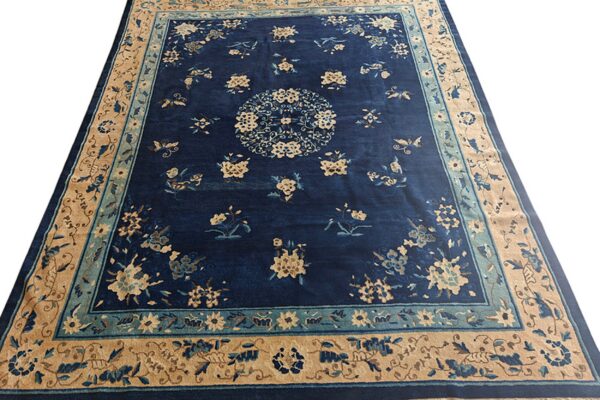 Navy blue rug featuring a repeating floral and butterfly pattern with tan and teal borders.