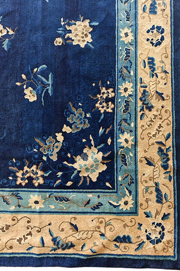 A deep blue rug with cream, teal, and tan floral designs along the corner border.