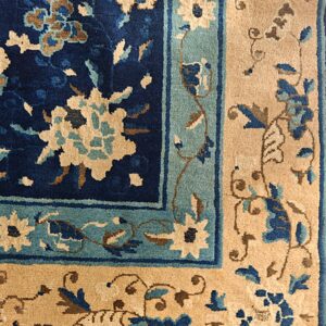 Floral pattern rug detail in navy, teal, and tan showing the plush pile and fringed edge.