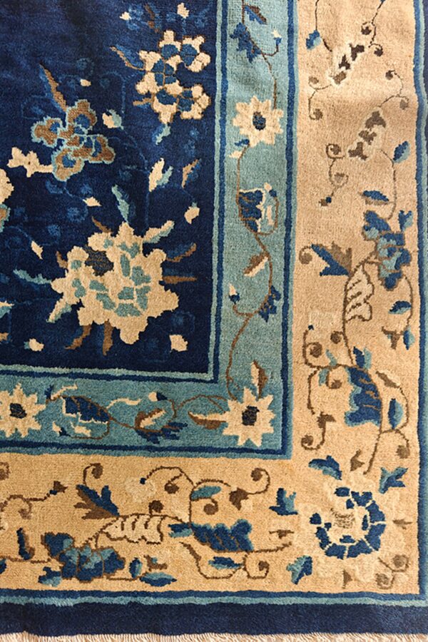 Floral pattern rug detail in navy, teal, and tan showing the plush pile and fringed edge.