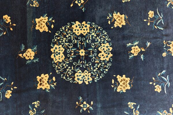 Navy blue rug featuring a circular tan and teal floral medallion surrounded by scattered sprays.