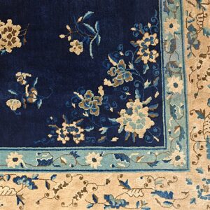 Deep blue high-pile rug corner with beige and light blue floral patterns and wide patterned borders.
