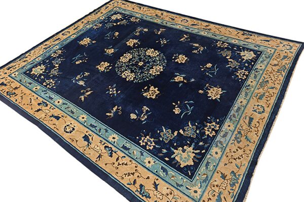 Navy blue rug with a central beige floral medallion and scattered flowers, framed by wide tan borders.