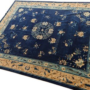 Deep indigo rug featuring a central medallion and beige floral motifs within ornate tan and teal borders.