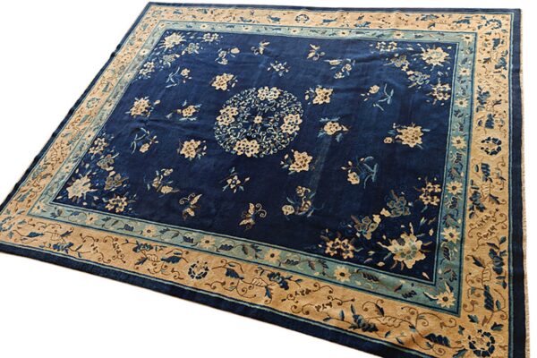 Deep indigo rug featuring a central medallion and beige floral motifs within ornate tan and teal borders.