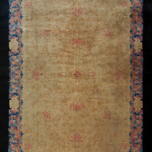 Light tan rug with tonal floral patterns and an ornate border detailed in coral, blue, and cream.
