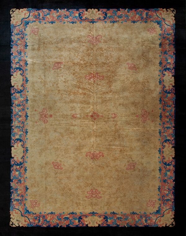 Light tan rug with tonal floral patterns and an ornate border detailed in coral, blue, and cream.