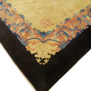 Close-up of a rug corner showing a yellow field, a peach border with blue scrolls, and a black outer edge.