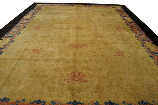 Golden yellow area rug with salmon medallions and a wide blue and coral patterned border.