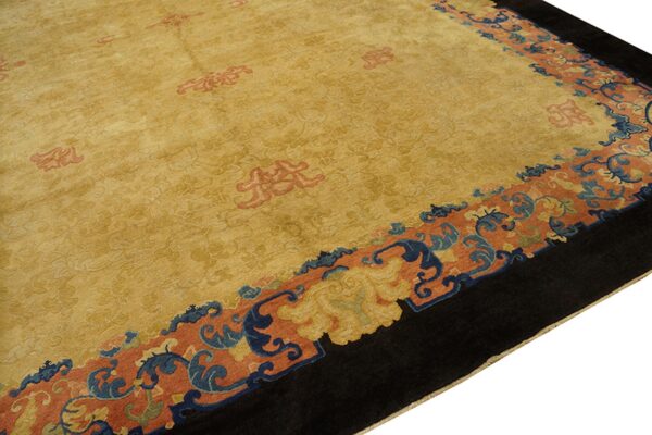 High-pile gold rug with large salmon and blue scrolled borders and a deep black edge.