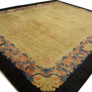 Gold area rug featuring subtle pink patterns and a wide scrolling border of coral, dark blue, and black.