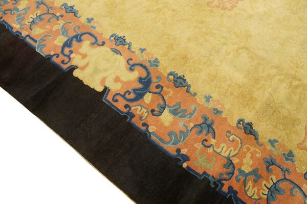 Golden yellow rug field bordered by a rust band with blue and yellow stylized floral motifs.