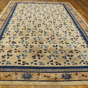 Light beige rug featuring a scattered blue leaf pattern and a complex blue border on hardwood flooring.