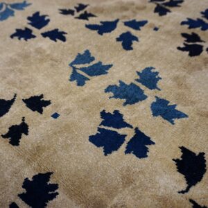 Plush tan rug with scattered stylized foliage motifs rendered in varying shades of blue.