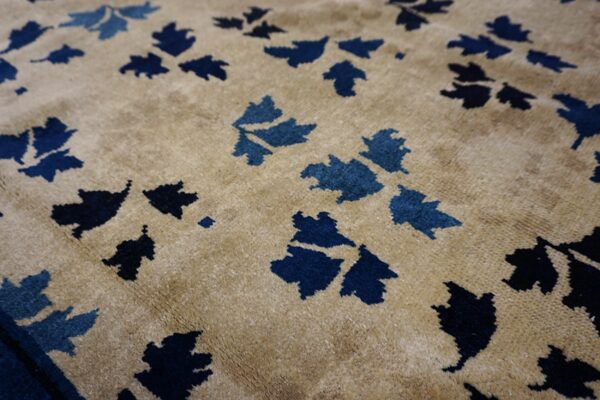 Plush tan rug with scattered stylized foliage motifs rendered in varying shades of blue.