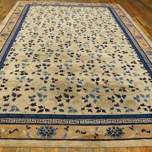 Light beige rug with scattered blue foliage and detailed blue borders displayed on warm wood planks.
