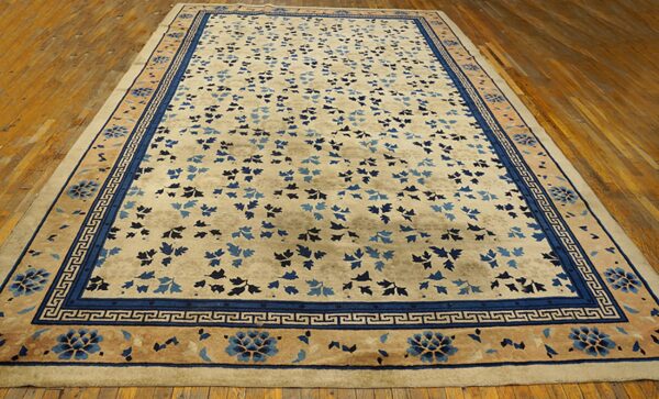 Light beige rug with scattered blue foliage and detailed blue borders displayed on warm wood planks.