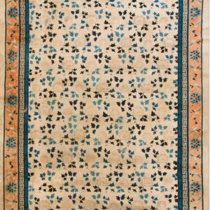 Beige rug with scattered blue and navy leaf patterns, framed by a wide peach floral border.