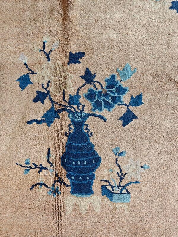 Tan rug texture with a deep blue vase and light blue floral pattern detail.