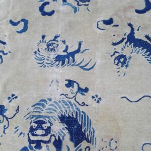 Blue stylized animal and cloud motifs pattern a pale cream, low-pile rug surface.