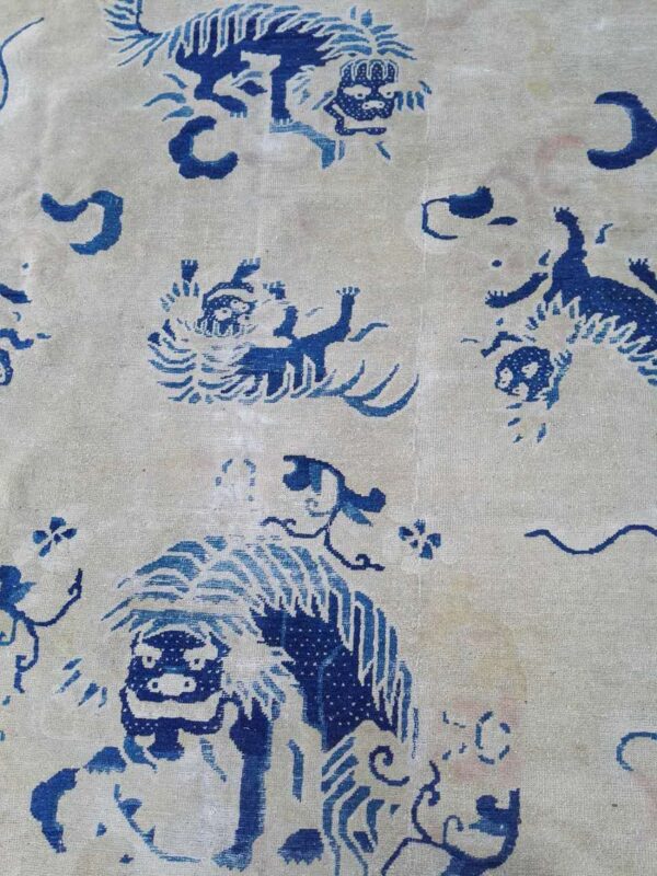 Blue stylized animal and cloud motifs pattern a pale cream, low-pile rug surface.