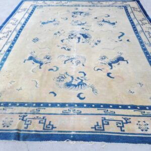 Low pile rug with a cream field and deep blue borders featuring mythological creatures and geometric patterns.