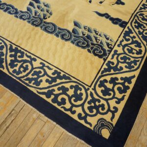 Beige and navy blue rug with carved borders and embossed field rests on distressed wood flooring.