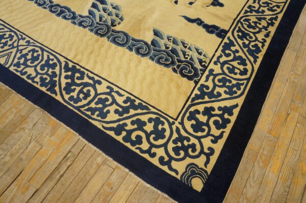 Beige and navy blue rug with carved borders and embossed field rests on distressed wood flooring.