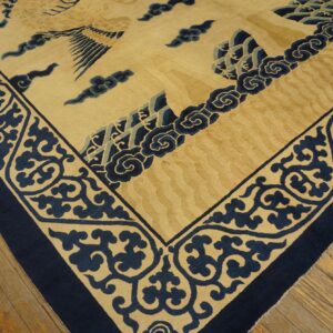 Contoured yellow and navy rug featuring detailed scroll borders and mythical designs on distressed wood floors.