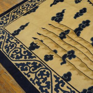 Cream and navy rug featuring a dense scroll border and carved cloud motifs on rustic wood flooring.