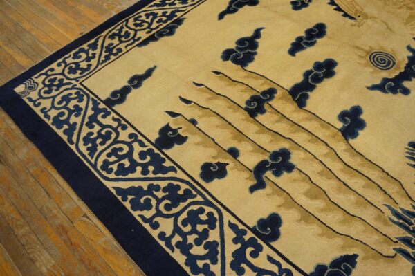 Cream and navy rug featuring a dense scroll border and carved cloud motifs on rustic wood flooring.