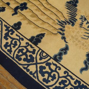 Beige and navy rug with scrolling borders and a large central cloud design rests on wood planks.