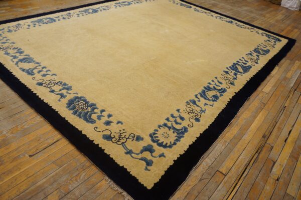 Pale yellow rug with a thick navy blue border featuring blue stylized floral designs on distressed wood planks.