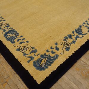 Yellow high-pile rug with a dense blue floral border detail and a dark edge, placed on wood flooring.